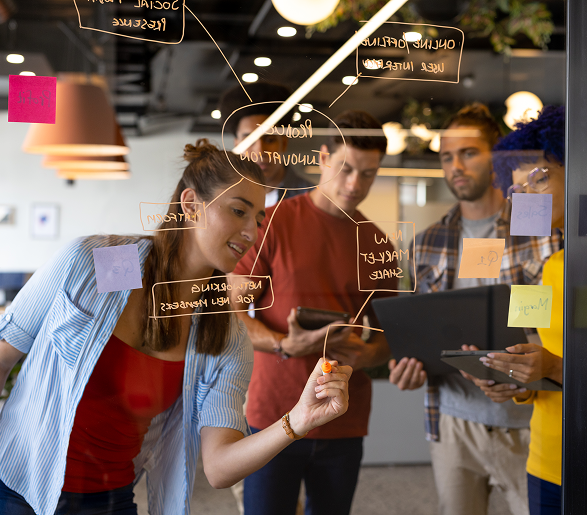 Imagen de una mujer joven haciendo brainstorming sobre un cristal con sus compañeros