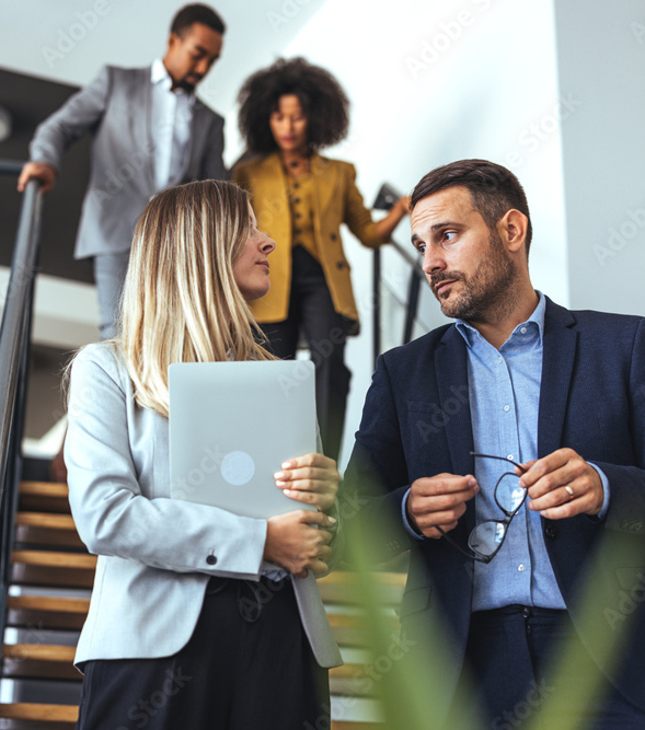 Hombre y mujer bajando escaleras con portatil