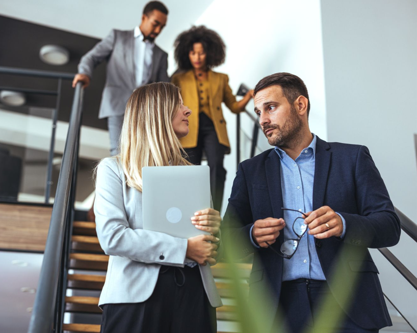 Hombre y mujer bajando escaleras con portatil
